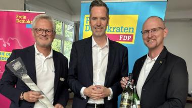 Daniel Farnung und Arne Wotrubez überreichen zum Dank einen Steinhuder Aal und eine Flasche Sekt der Neustädter Sektkellerei Dupres